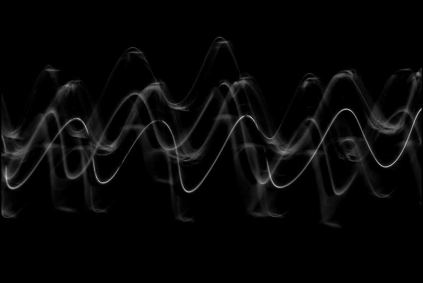 Audio waveform on black background, white traces showing speech-like amplitude variation